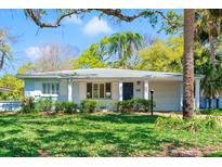 Charming single-story home featuring a well-manicured lawn, lush landscaping, and a welcoming blue front door at 8285 28Th N Ave, St Petersburg, FL 33710