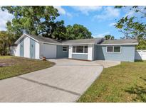 Newly renovated light blue house with white accents, showcasing a landscaped yard at 1004 Greenleaf Way, Tarpon Springs, FL 34689