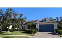 Charming home with a blue garage door, landscaped yard, and paver driveway at 917 Riverscape St, Bradenton, FL 34208