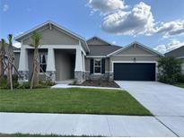 Charming single-story home boasts stone accents, a dark garage door, and freshly landscaped front yard at 17434 Crisp Apple Ln, Land O Lakes, FL 34638