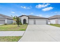 Charming single-Gathering home featuring a well-manicured front yard and a spacious two-car garage at 13557 Willow Bluestar Loop, Riverview, FL 33579