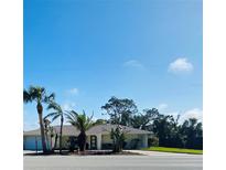 Exterior view of home featuring mature palm trees, tropical foliage, a well manicured lawn and a sunny blue sky at 933 Harbor S Dr, Venice, FL 34285