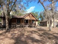 Charming log cabin with a covered porch surrounded by trees and spacious yard at 25327 Celmar St, Brooksville, FL 34601