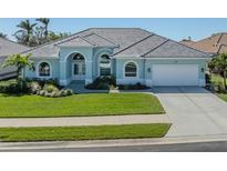 Charming single-story home with a manicured lawn, tile roof, arched windows, and a two-car garage at 519 Purslane Pt, Venice, FL 34293