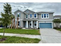 Charming two-story home features a blue garage door, blue shutters, a manicured lawn, and a classic facade at 9572 Brave Buck Ave, Land O Lakes, FL 34638