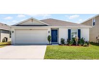 Charming single-story home featuring a well-maintained lawn, a two-car garage, and a vibrant blue front door at 38370 Sonnet Landing Ave, Zephyrhills, FL 33540