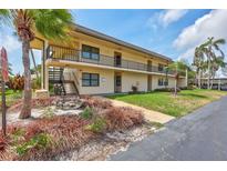 Two-story condo building with tropical landscaping, exterior stairs, and a view of the parking area at 12300 Vonn Rd # 1102, Largo, FL 33774