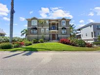 Stunning three-story home featuring manicured landscaping, dual balconies, and a grand entrance at 7020 Hawks Harbor Cir, Bradenton, FL 34207