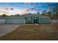 Charming home featuring a three car garage, manicured lawn, and a beautiful entrance at 11344 Gallinule Ave, Weeki Wachee, FL 34613