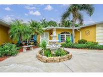 Charming home featuring a front yard with lush landscaping, a fountain, and a sitting bench at 401 Sunset Dr, Venice, FL 34285