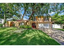 Two-story home with a well-manicured lawn, mature trees, and brick driveway at 16601 W Course Dr, Tampa, FL 33624