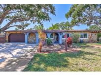 Charming single-story home with stone accents, blue facade, mature trees, and landscaped front yard at 6443 34Th N Ave, St Petersburg, FL 33710