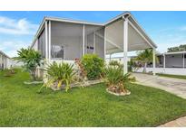 Well-maintained home featuring a covered carport, screened-in porch, and lush landscaping at 9790 66Th N St # 89, Pinellas Park, FL 33782