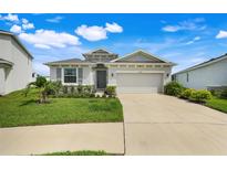 Charming single-story home featuring manicured lawn, neutral stucco, and a two-car garage at 13797 Wineberry Dr, Dade City, FL 33525