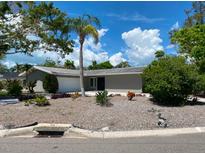 Well-maintained single-story home featuring a grey facade, complemented by a lush palm tree in the front yard at 4571 Clearwater Harbor S Dr, Largo, FL 33770