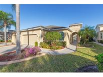 Tan two-car garage home with landscaping and walkway at 2429 Nottingham Greens Dr # 118, Sun City Center, FL 33573