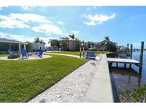 Spacious backyard features a lawn, dock, a fire pit and water access for relaxing and entertaining at 817 Blue Heron Blvd, Ruskin, FL 33570