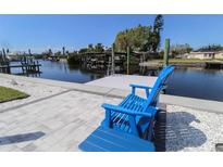 Inviting backyard with waterfront views and a dock, complete with comfortable Adirondack chairs at 817 Blue Heron Blvd, Ruskin, FL 33570