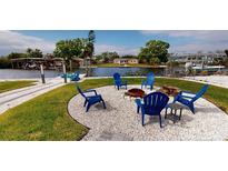 Inviting outdoor space with blue chairs around a fire pit, perfect for enjoying waterfront views and outdoor gatherings at 817 Blue Heron Blvd, Ruskin, FL 33570