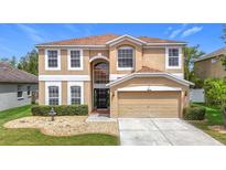 Charming two-story tan home with a well-manicured lawn and a two-car garage at 18441 New London Ave, Land O Lakes, FL 34638