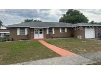 Single-story home featuring a white double-door entry, neutral siding, green grass, and a one-car garage at 7160 Lockwood St, Spring Hill, FL 34606