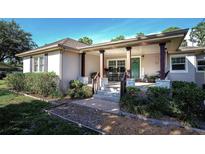 Charming home featuring a covered front porch, adorned with rocking chairs and stone-accented columns at 18101 Boy Scout Rd, Odessa, FL 33556