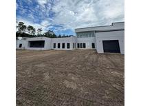 Modern white home featuring a sleek design, expansive windows, and a spacious, unfinished front yard at 2518 Sunset Ln, Lutz, FL 33559
