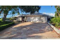 Inviting single-story home with a two-car garage and a well-maintained front yard with mature trees and stone-paved driveway at 891 Island Way, Clearwater Beach, FL 33767