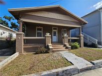 Charming single-story home featuring a covered front porch with brick supports and inviting curb appeal at 917 E 15Th Ave, Tampa, FL 33605