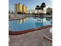 Beautiful outdoor pool with lounge chairs, tables, and palm trees in a condominium community at 4750 Cove Cir # 502, St Petersburg, FL 33708