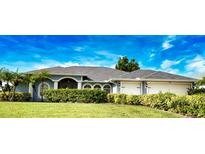Charming one-story home with manicured lawn and a 2-car garage, framed by lush landscaping under a bright blue sky at 536 Boundary Blvd, Rotonda West, FL 33947