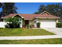 Single-story house with a red roof, white garage door, and landscaping at 7801 Glascow Dr, New Port Richey, FL 34653