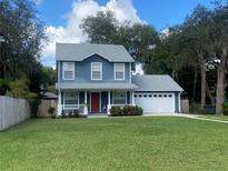Two-story house with blue siding, red door, and a well-maintained lawn at 6704 N 13Th St, Tampa, FL 33604