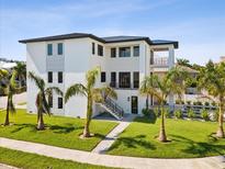 Modern home exterior with palm trees and landscaped lawn at 116 Wimbledon Ct, Redington Shores, FL 33708