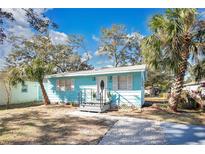 Charming light blue house with landscaped yard and palm trees at 1820 Douglas Ave, Clearwater, FL 33755