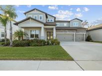 Two-story home with gray siding, three-car garage, and landscaped lawn at 11449 Owasee Trails Pl, Riverview, FL 33569