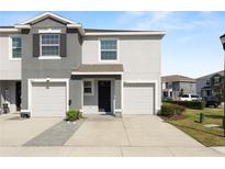 Contemporary townhome featuring a two-car garage, neutral stucco exterior, and well-maintained landscaping at 8680 Falling Blue Pl, Riverview, FL 33578