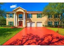 Inviting two-story home featuring a red driveway, well-maintained lawn, and traditional architecture with a bright red front door at 11175 Hyde St, Weeki Wachee, FL 34614