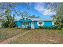 Charming blue cottage-style home with white trim, an American flag and a brick walkway to the front door at 1000 Michigan Blvd, Dunedin, FL 34698