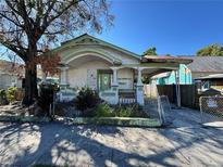 Neglected single-story home featuring a fenced yard and covered parking at 921 E 12Th Ave, Tampa, FL 33605