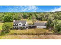 Sprawling two-story white farmhouse with a stone chimney, front porch and expansive grounds at 8922 Pritcher Rd, Lithia, FL 33547