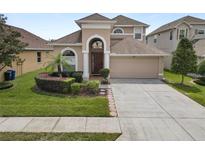 Charming home showcasing manicured lawn, circular garden, and a two-car garage, offering curb appeal and convenience at 30816 Pumpkin Ridge Dr, Wesley Chapel, FL 33543