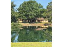 A serene view of the home reflected in a pond, surrounded by lush greenery and mature trees at 4101 N Forbes Rd, Plant City, FL 33565