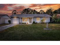 Charming one-story home with a well-manicured lawn and a picturesque sunset backdrop at 13032 Cumberland Dr, Largo, FL 33773
