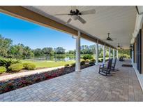 Spacious covered porch with ceiling fans offers views of the beautiful landscaped yard and waterfront at 701 E 60 Hwy, Plant City, FL 33567