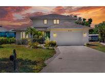 Two-story home featuring a lush landscaped yard, two car garage, and a beautiful sunset at 4116 4Th Ne Ave, Bradenton, FL 34208