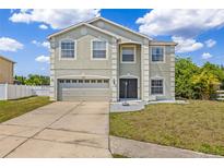 Two-story home featuring a two-car garage, neutral paint, manicured lawn, and classic architectural details at 12214 Citrus Leaf Dr, Gibsonton, FL 33534