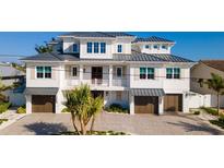 Stunning three-story coastal home with gray roof, white siding, and attached garages at 531 68Th St, Holmes Beach, FL 34217