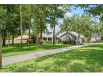 Charming home featuring mature trees, a long driveway, and well-maintained landscaping on a sunny day at 9912 Pine Leaf Ln, Dade City, FL 33525