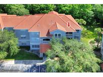 Three-story condo features a red tiled roof and a gray exterior surrounded by lush trees at 18001 Richmond Place Dr # 337, Tampa, FL 33647